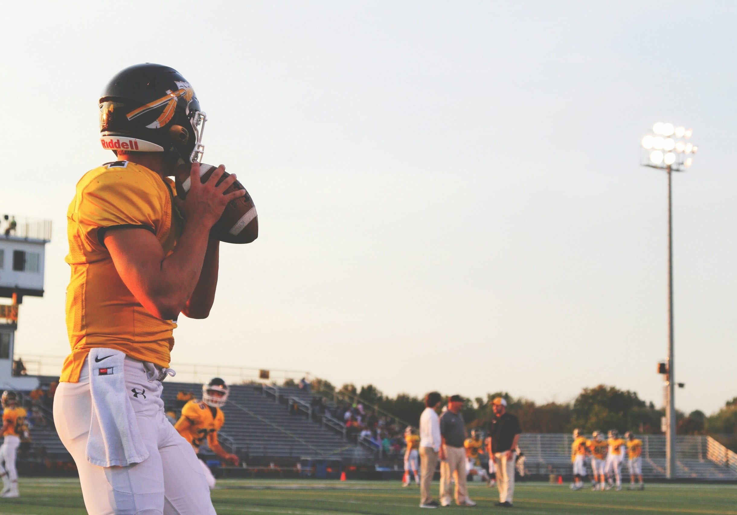 riley-mccullough-m5pz9D6MfUk-unsplash A quarterback in a yellow jersey preparing to throw the ball